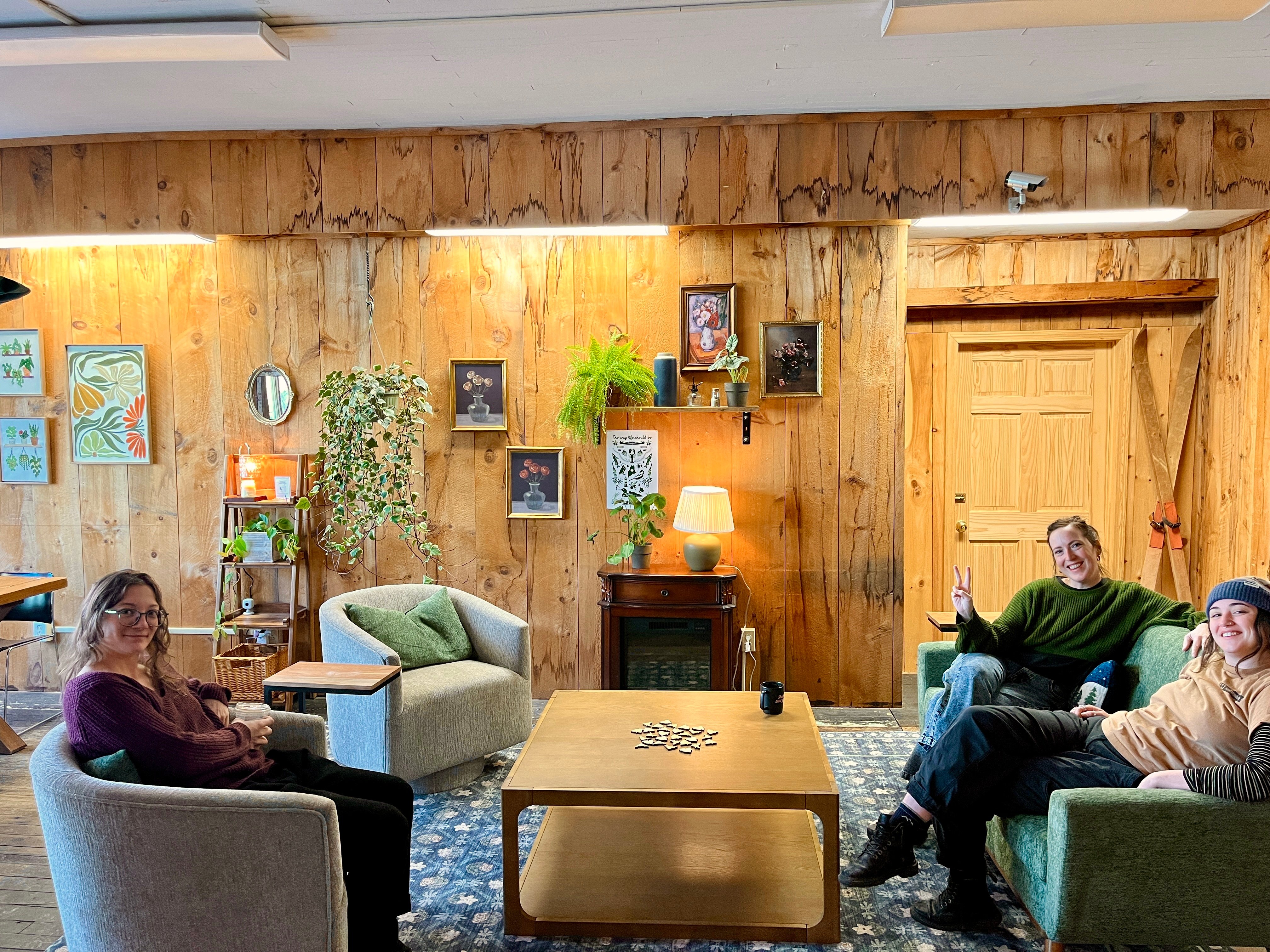 Three people relaxing in a cozy lounge area at The Study coworking space in Kingfield, Maine, showing the community atmosphere and comfortable seating available during a day pass visit.