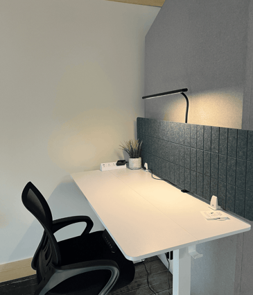 A flexible workstation with adjustable desk, noise cancelling sound panel, task lighting, comfortable task chair, and surge protector.