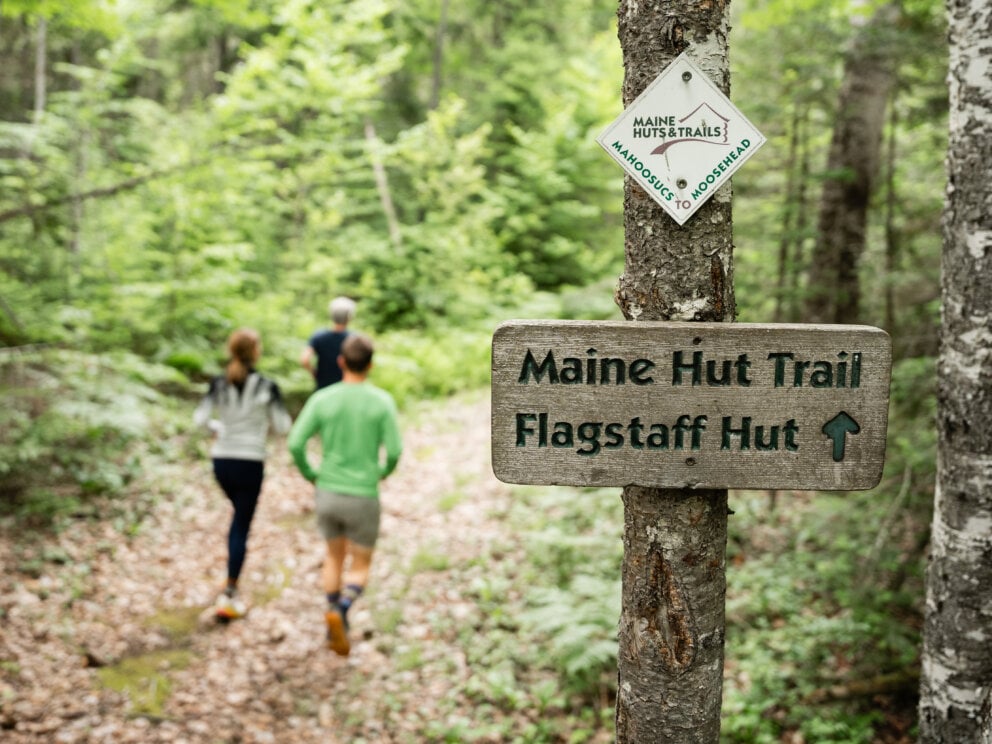 Three hikers on the Maine Hut Trail heading toward Flagstaff Hut, part of the Maine Huts & Trails 80-mile backcountry trail system in Western Maine
