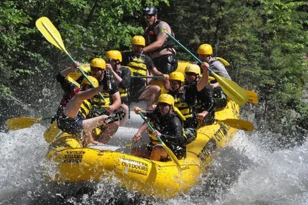 Rafters paddling through whitewater on a Northern Outdoors guided rafting trip on the Kennebec River in Maine